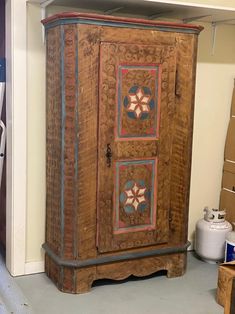 an old wooden cabinet with decorative designs on it's doors and shelves in a storage room