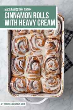 cinnamon rolls with heavy cream in a casserole dish on a marble counter top