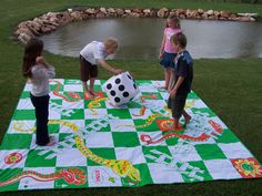 three children are playing with a giant ball on a checkered blanket in the grass