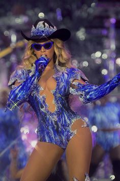 a woman in a blue bodysuit and cowboy hat on stage