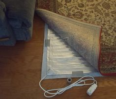 an open laptop computer sitting on top of a wooden floor next to a pile of pillows