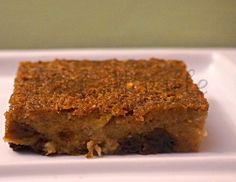 a piece of cake sitting on top of a white square plate in front of a green wall