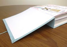 a stack of papers sitting on top of a wooden table next to a computer mouse