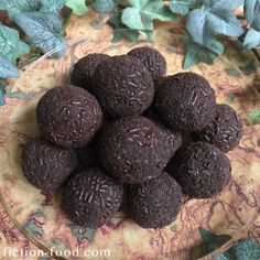 a glass bowl filled with chocolate truffles on top of a leaf covered table