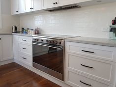 a kitchen with white cabinets and stainless steel stove top oven in the middle of it