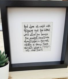 a black frame with a poem in it and a potted plant next to it