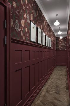 an empty hallway with red doors and floral wallpaper