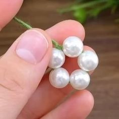 a person is holding some white pearls in their fingers and they are on the table