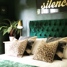 a bed with green velvet headboard and leopard print pillows on it's sides