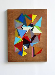 an abstract painting on a wooden panel with multiple colors and shapes in the center, against a white wall