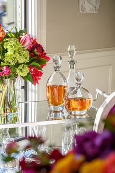 vases filled with flowers sitting on top of a glass table next to a mirror