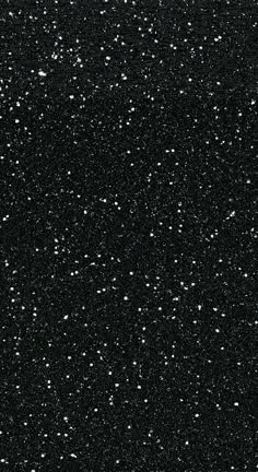 black and white photograph of snow flakes on a dark night sky with no clouds