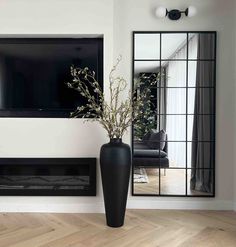 a large black vase sitting next to a mirror on the wall in front of a fireplace