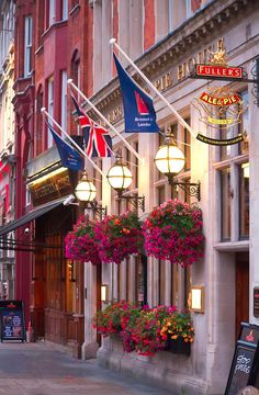 the outside of a building with flowers hanging from it's windows and flags flying in the air