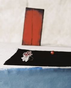 a ring sitting on top of a table next to a red piece of wood and a black mat