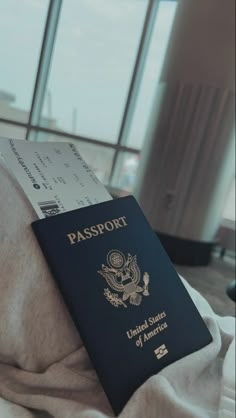 a passport sitting on top of a bed next to a window