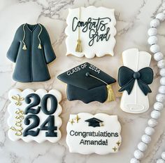 decorated cookies with graduation decorations on a marble countertop, including congratulationss and badges