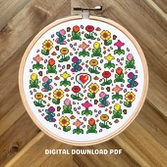 a cross stitch pattern with flowers in the center on a wooden hoop hanging from a wall