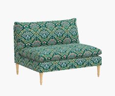 an upholstered couch with green and blue floral print on the back, in front of a white background