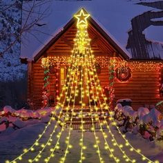 a christmas tree is lit up in front of a cabin