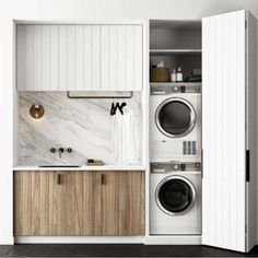 a washer and dryer in a small room with white walls, wood cabinets and marble counter tops