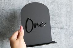 a person holding up a piece of paper with the word one cut out on it