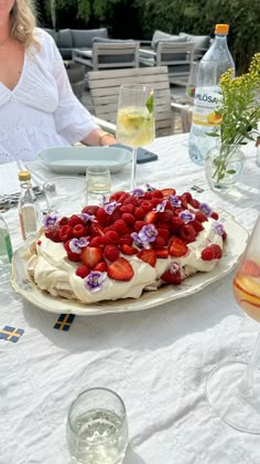 a woman sitting at a table with a plate of strawberries and flowers on it