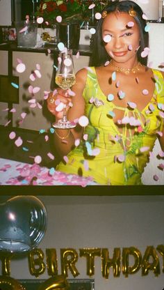 a woman holding a wine glass in front of her face and confetti on the table