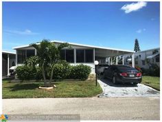 a car parked in front of a house with palm trees on the side of it