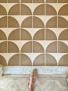 a person's feet are standing in front of a wall with arches on it