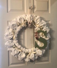 a white wreath with the letter s on it hanging on a front door decorated with ruffles