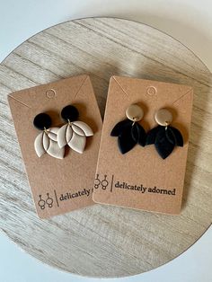 two pairs of black and white earrings sitting on top of a wooden table next to each other