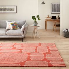 a living room with an orange rug and couches in the corner, along with pictures on the wall