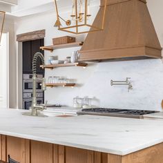 a kitchen with an island, stove and hanging light fixture in the middle of it