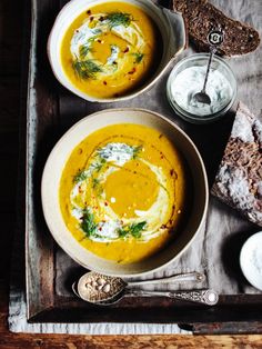 two bowls of soup and bread on a tray