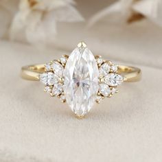 an engagement ring with a pear shaped diamond surrounded by small white flowers and gold accents