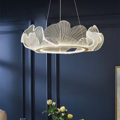 a chandelier hanging over a dining room table with flowers in vases on it