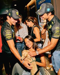 two men and a woman holding a dog in their hands at an event with other people looking on