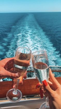 two people toasting with wine glasses on a boat in front of the ocean and blue sky