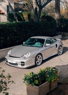 a silver sports car parked in front of some bushes