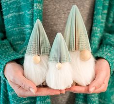 three small white and green gnome hats held in their hands with one wearing a gray sweater