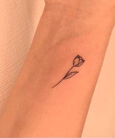 a small flower tattoo on the wrist is shown in black and grey ink, with a single tulip at the center