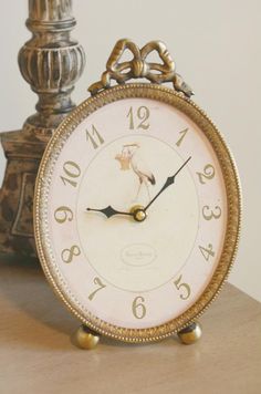 an old fashioned clock sitting on top of a wooden table next to a candle holder