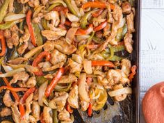 chicken fajita with peppers and onions on a baking sheet next to an orange towel