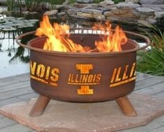 a fire pit sitting on top of a wooden deck next to a pond with water