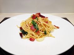 pasta with bacon and spinach on a white plate