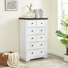 a white chest of drawers sitting next to a potted plant in a living room