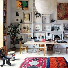 a living room filled with lots of furniture and pictures on the wall next to a table