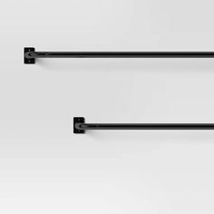 two black metal shelf brackets on a white wall