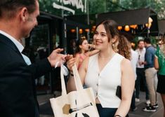 a woman holding a shopping bag talking to a man in a black suit and tie